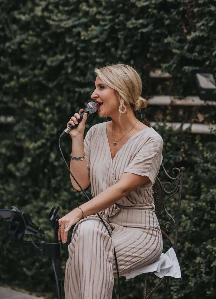 Hochzeitssängerin Ola Stovall singt sitzend mit Mikrofon bei einer Trauung